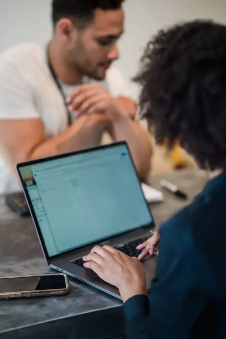 Two adults in an office setting collaborating on a project using a laptop. Perfect for business and teamwork concepts.