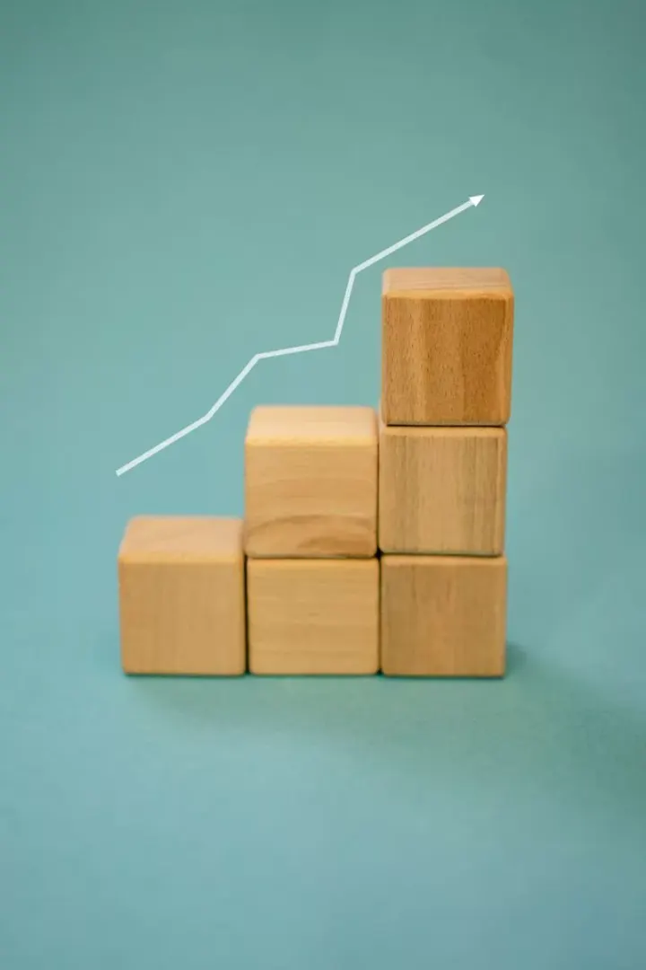 Wooden blocks forming a staircase with an upward arrow symbolizing growth and progress.