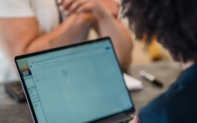Two adults in an office setting collaborating on a project using a laptop. Perfect for business and teamwork concepts.