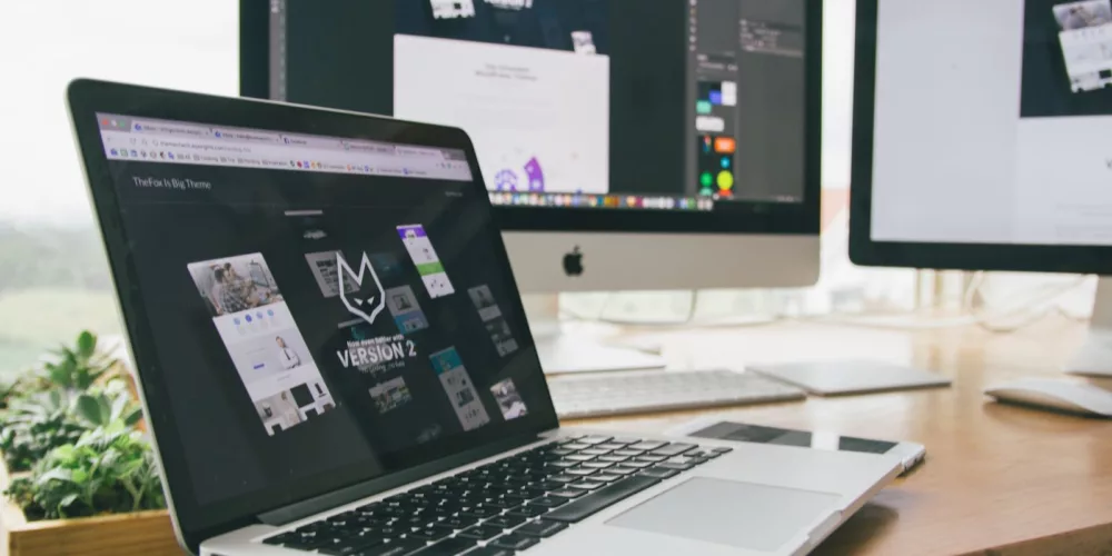 A stylish workspace featuring a laptop and monitors displaying design software.