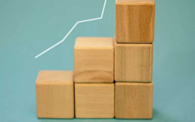 Wooden blocks forming a staircase with an upward arrow symbolizing growth and progress.